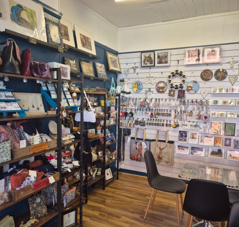Display of handmade gifts. White wall display and black shelf units in store full of different handmade gifts available to buy at Creative Cuppa.